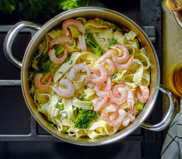 Creamy pasta with peas, broccoli and prawns